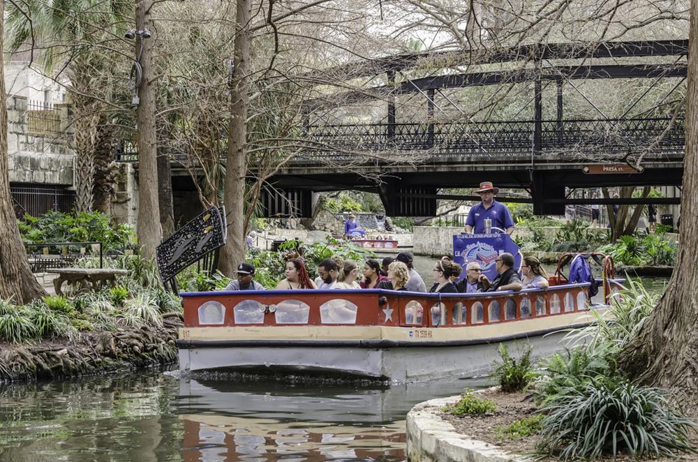 Sightseers enjoy leisurely boat tours along the San Antonio River as pilot-guides describe historic and architectural features of the popular River Walk