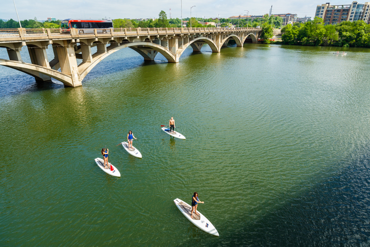 Paddle boarders cruising along the Colorado River by the Lamar Street Bridge